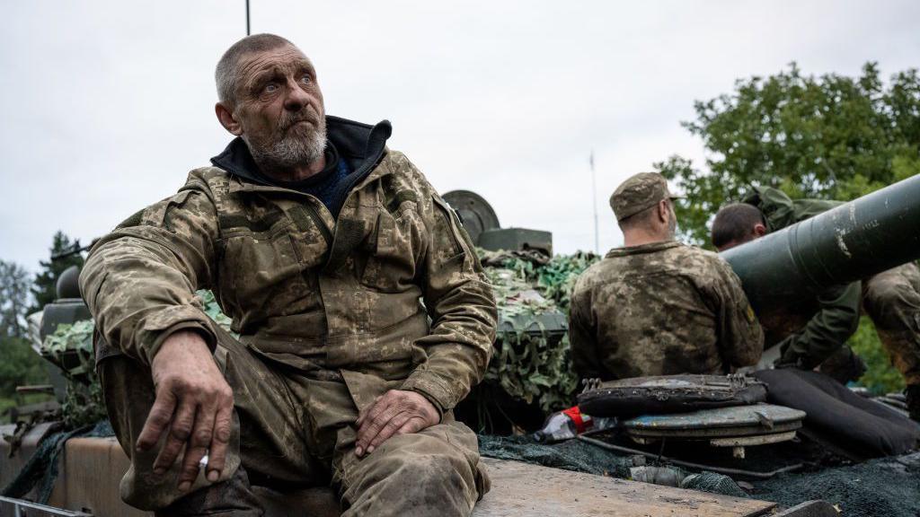 Exhausted Ukrainian soldiers sit on a tank