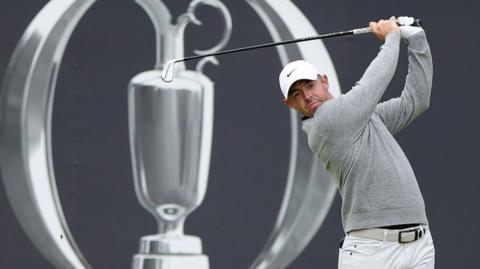 Rory McIlroy delivers an iron shot with the Open Championship logo behind him