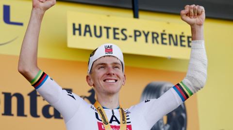 Tadej Pogacar with his arms aloft on the podium after winning stage 12 of the 2025 Tour de France