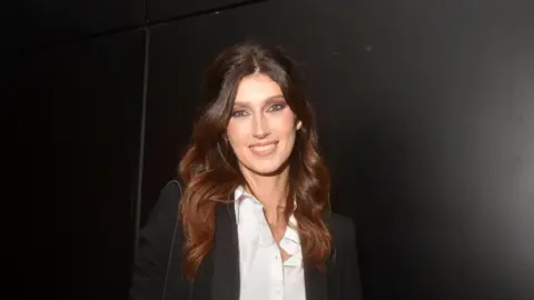Sophie Vouzelaud with long auburn hair and wearing a white short and black jacket in Paris, France, in October 2023.